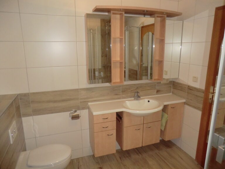 Badezimmer mit Waschbecken, Spiegel und WC in Ferienwohnung Brak.