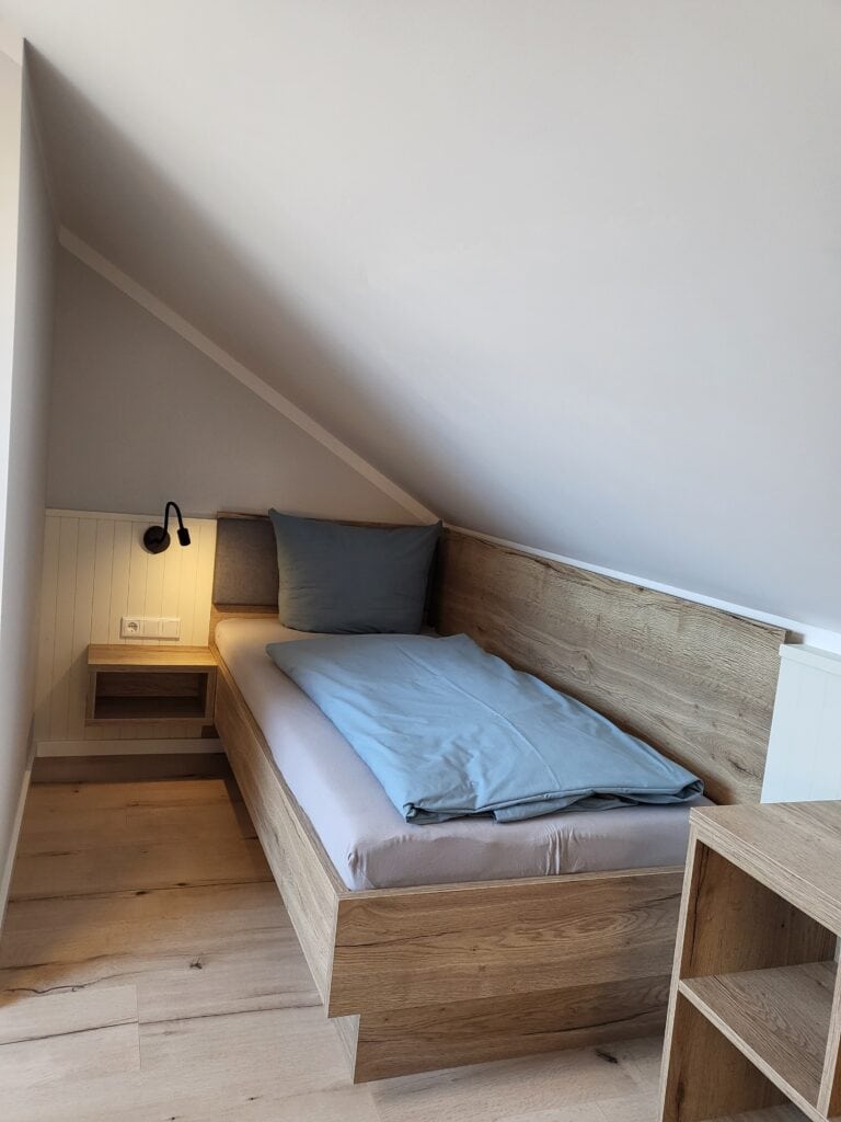 Gemütliches Schlafzimmer mit Dachschräge, komfortables Bett und moderne Einrichtung in Ferienwohnung.