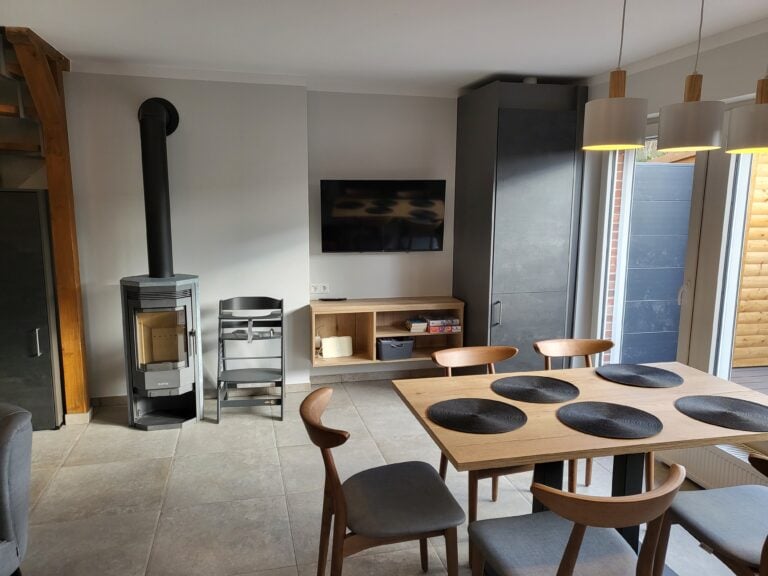 Modernes Wohnzimmer mit Esstisch, Kamin und TV in Ferienwohnung Brake.