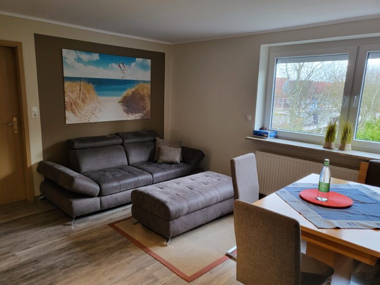 Gemütliches Wohnzimmer mit modernem Sofa, Blick auf den Garten, ideal für Ferienwohnungen in Brake.