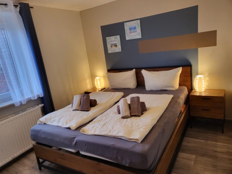 Gemütliches Doppelzimmer mit modernen Möbeln, angenehmer Beleuchtung und Blick auf das Fenster.