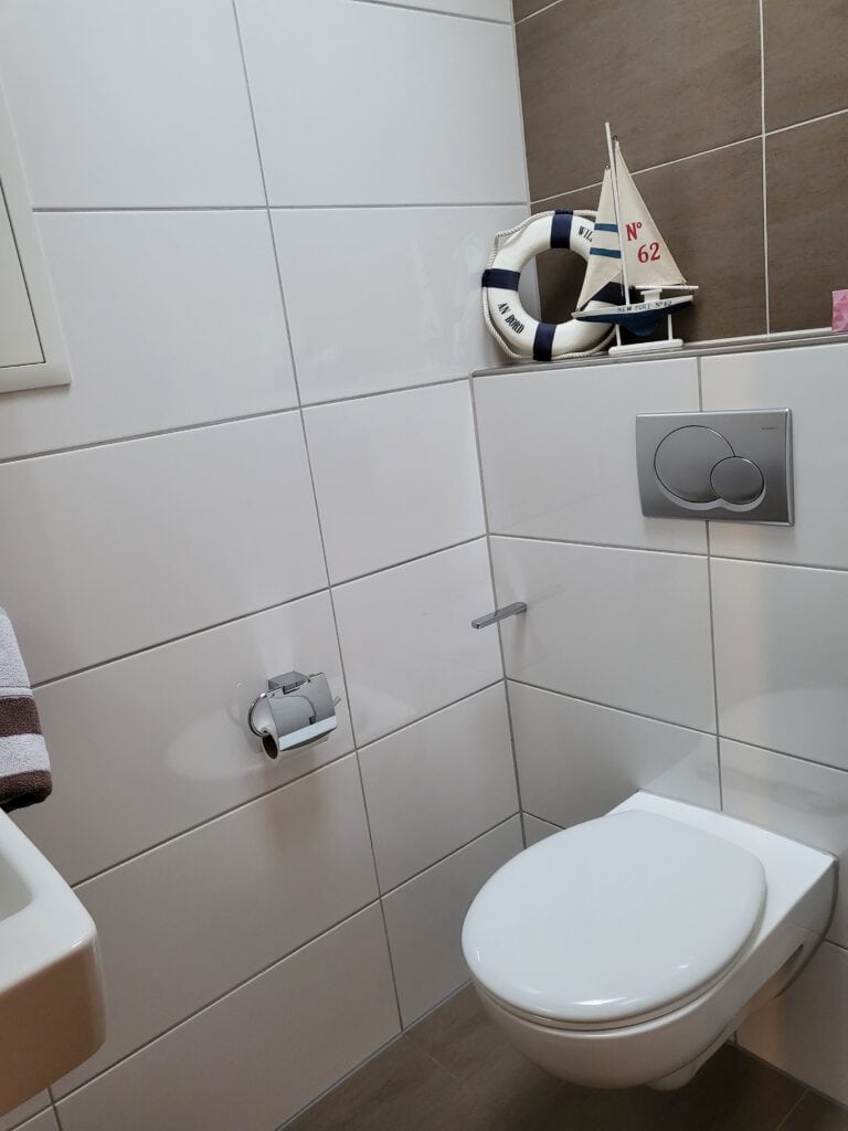 Modernes Badezimmer in Ferienwohnung Brak mit WC und maritimen Dekorationen.