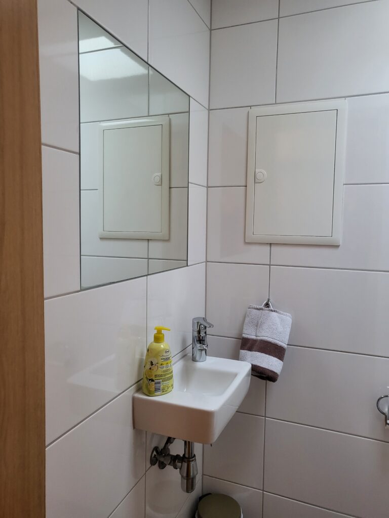 Ferienwohnung Brake Badezimmer mit Waschbecken, Spiegel und Handtuchhalter.