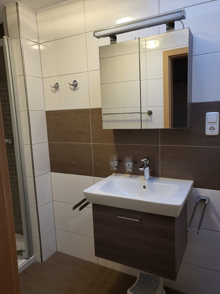 Modernes Badezimmer mit Waschbecken, Spiegel und Handtuchhaltern in Ferienwohnung Brak.