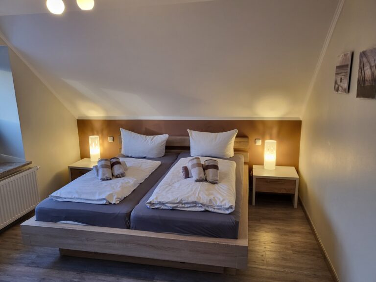 Schlafzimmer mit Doppelbett, bequemen Kissen und stilvoller Beleuchtung in Ferienwohnung Brak.