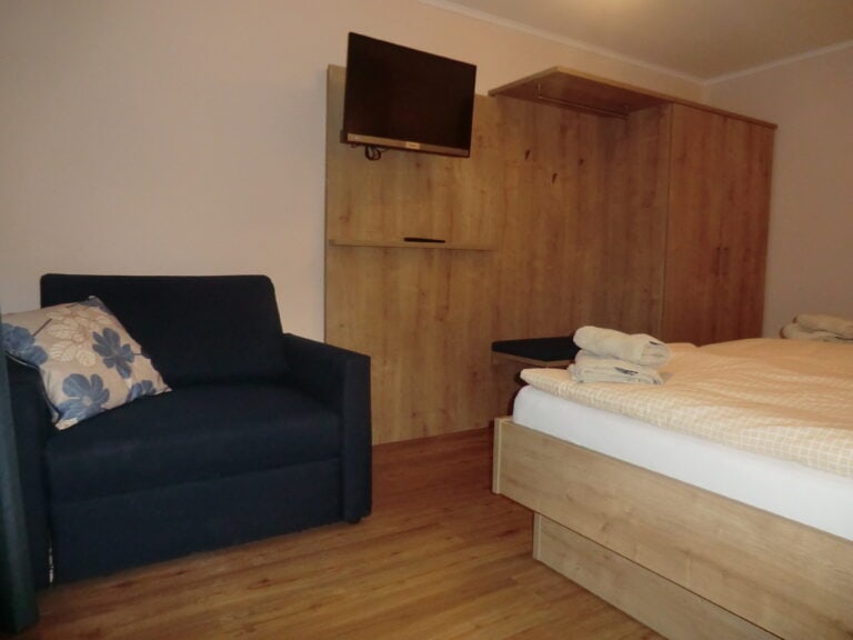 Ferienwohnung Schlafzimmer mit Fernseher, Couch und komfortablem Bett in Brak.