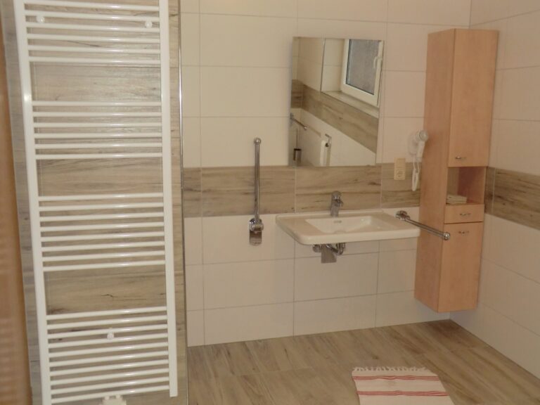 Modernes Badezimmer in Ferienwohnung mit Waschbecken, Spiegel und Handtuchheizung.