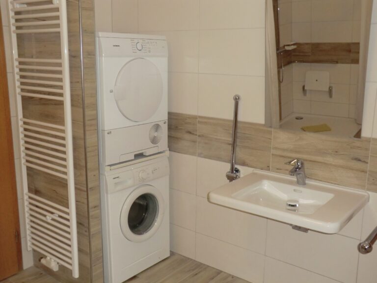 Waschmaschine und Waschbecken in Ferienwohnung Brak, ideal für komfortable Unterkünfte.
