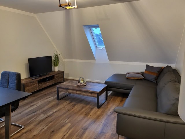 Gemütliches Wohnzimmer mit Sofa, TV und Fenster in der Ferienwohnung Brak, ideal für einen entspannt.