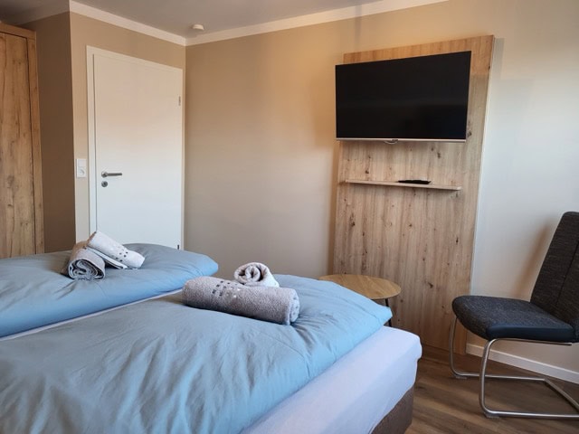 Schlafzimmer mit Fernseher, Betten und gemütlicher Atmosphäre in Ferienwohnung Brak.