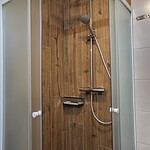 Duschkabine in Ferienwohnung mit Holzoptik, ideal für entspannte Urlaubstage.