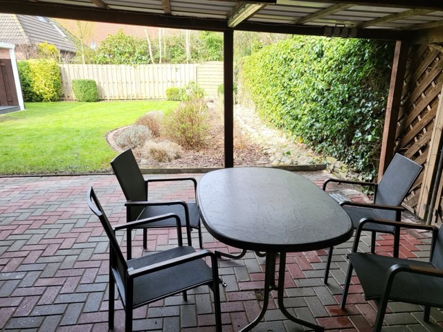Gartenbereich mit Esstisch, Stühlen und Überdachung in Ferienwohnung Brake, ideal für entspannte Stu.