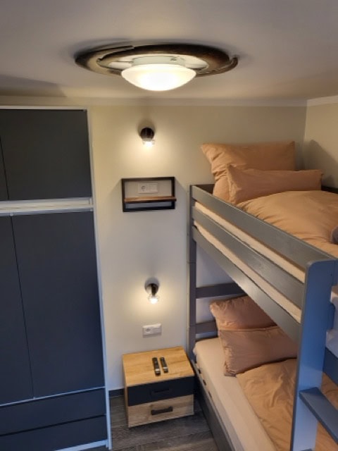 Schlafzimmer mit Etagenbett, ideal für Familien, inklusive Stauraum und moderner Beleuchtung.